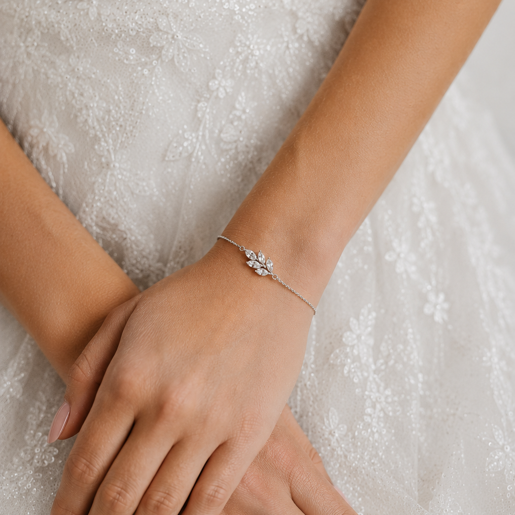 Zartes, filigranes Tilla Brautarmband in 925 Sterlingsilber mit Zirkonia- Blatt am Handgelenk einer Braut vor dezentem Spitzenkleid getragen