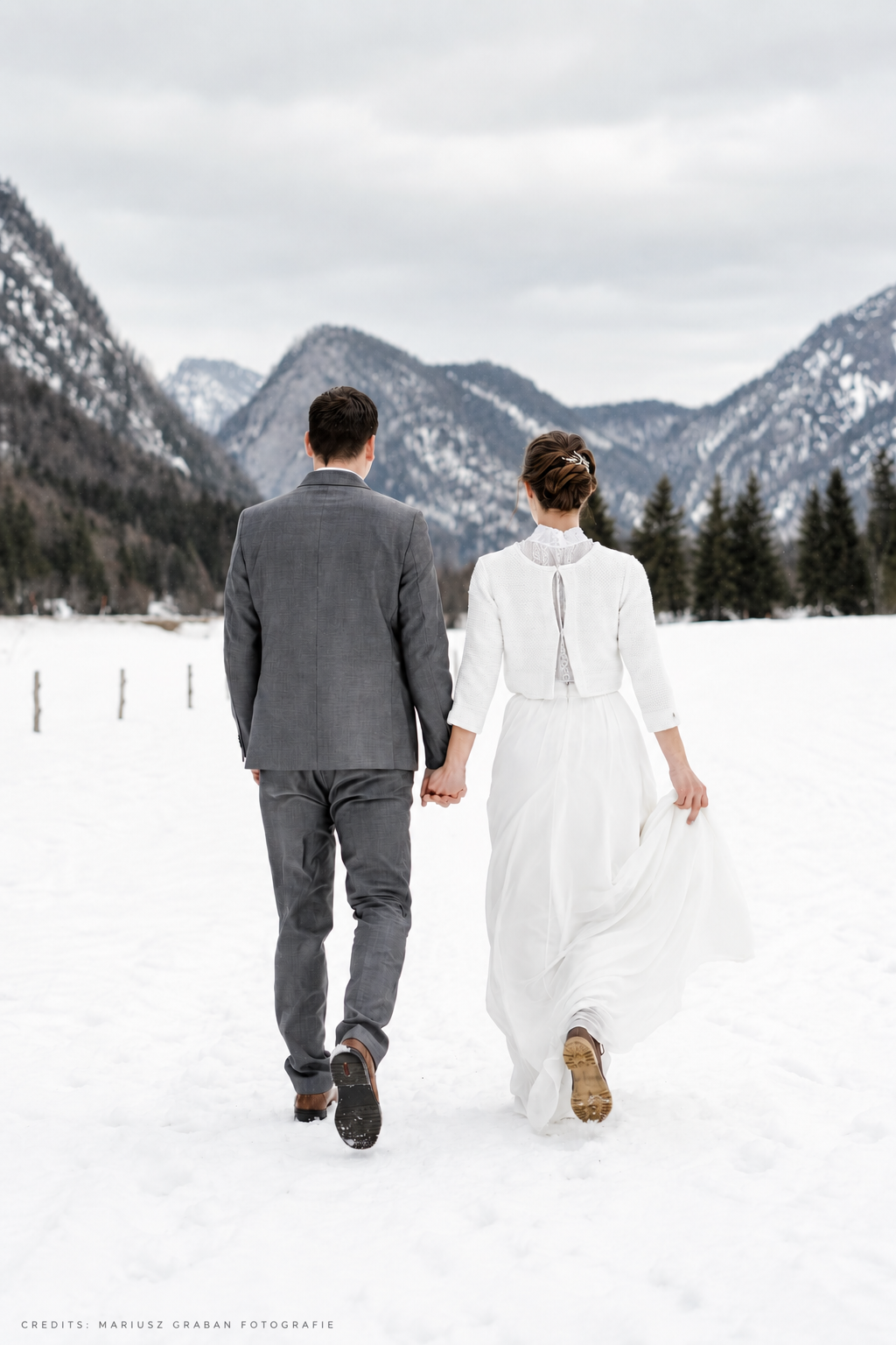 Brautpaar bei einer Winterhochzeit im Schnee vor verschneiter Bergkulisse