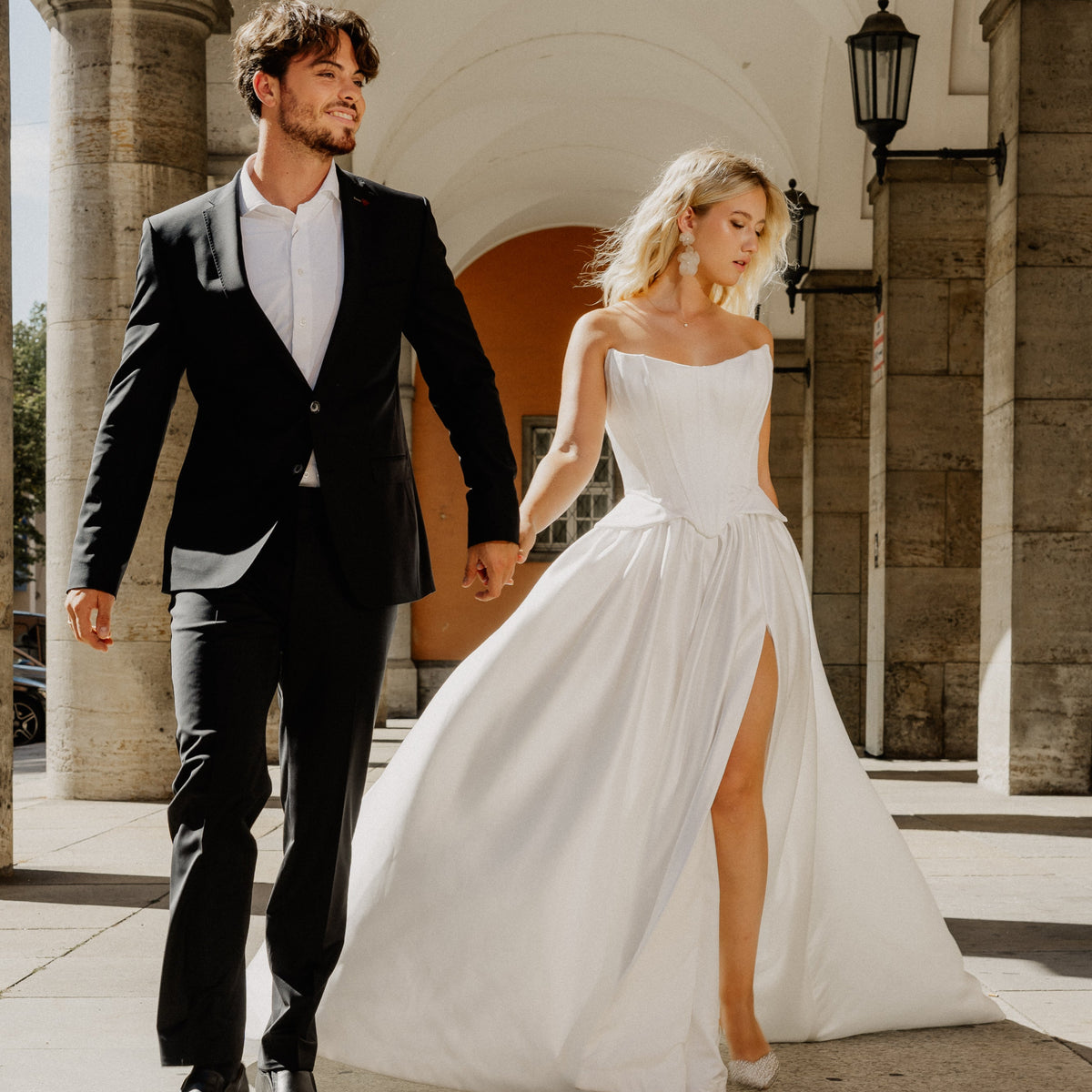 Modelpaar in München - sie trägt elegante Statement Brautohrringe Carry aus 925er Sterlingsilber 18K vergoldet mit einer großen und einer kleinen, hängenden Blüte
